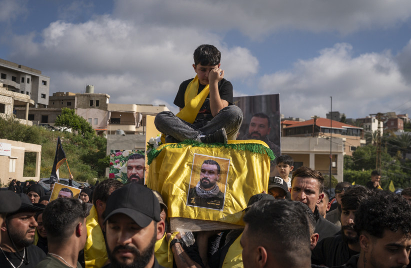 The son of a slain Hezbollah fighter sits on his coffin as it is carried during a funeral ceremony last month in Lebanon. After more than two years of war with Israel, analysts believe that Hezbollah now lacks power and legitimacy.