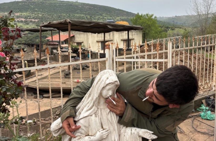 AN IDF soldier puts a cigarette in the mouth of a statue of the Virgin Mary.