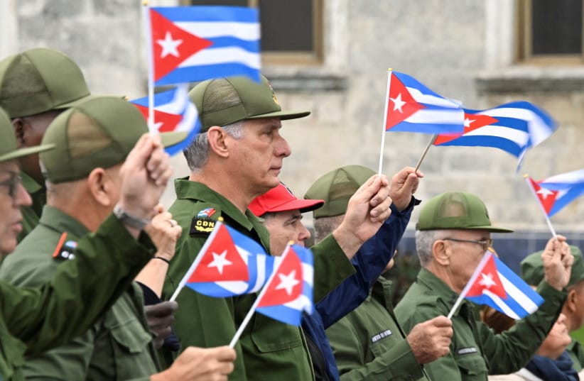 Cuba's President Miguel Diaz-Canel waves a Cuban flag alongwith others during a march outside the U.S. Embassy to protest against what they denounce as U.S. aggression in the region, following the capture of Venezuelan leader Nicolas Maduro and the killing of Cuban soldiers on January 16, 2026.