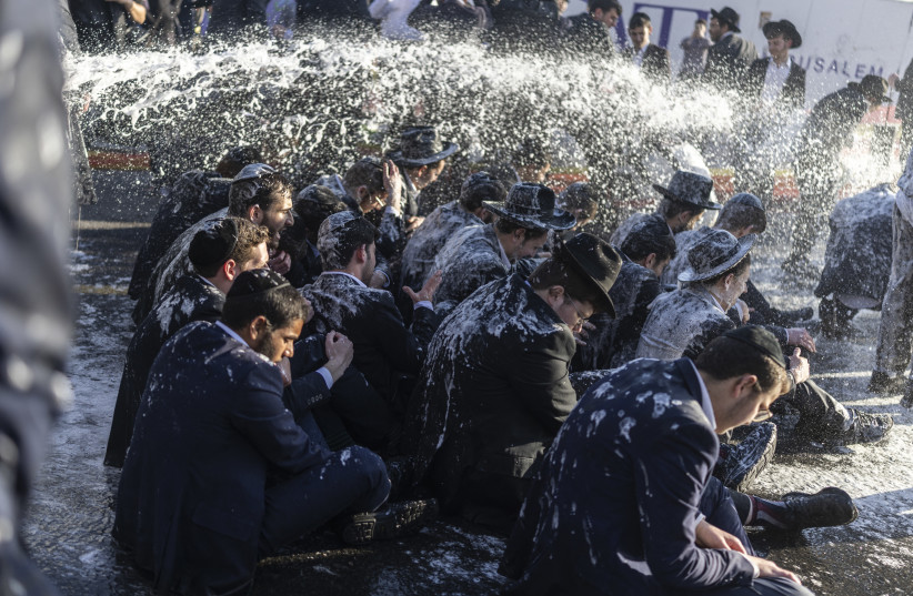 Ultra-Orthodox Jews sit while being sprayed by a water cannon during a protest against conscription at the entrance to Jerusalem, on April 29. One of the major issues likely to shape election discourse is the role of the ultra-Orthodox sector in Israel’s future.