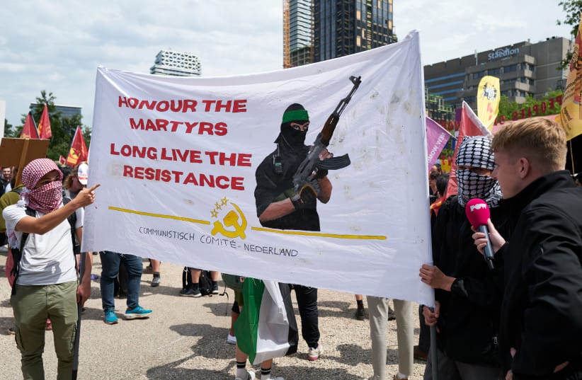 protesters and members of the Communist Comity of The Netherlands hold a banner in support of Hamas fighters on June 22, 2025 in The Hague, Netherlands.