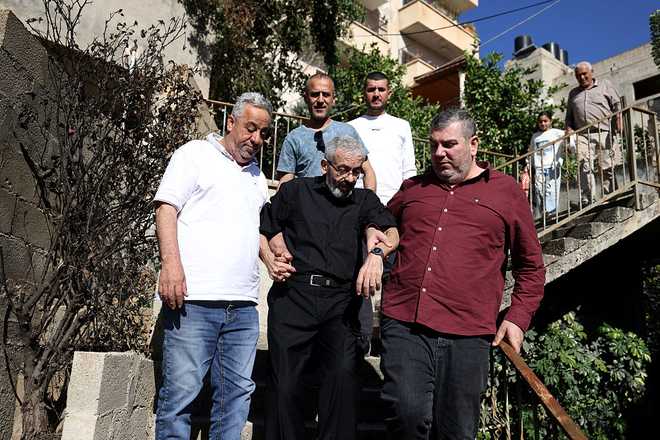 PALESTINIAN-ISRAEL-CONFLICT-MEDIA-PRISONER Palestinian journalist Ali al-Samoudi (C) is helped down the stairs at his home in the northern city of Jenin, in the Israeli-occupied Palestinian West Bank on May 1, 2026. Sixty-year-old Al-Samoudi was released following one-year in detention in the Israeli Naqab Prison, located in southern Israel. He was released and checked at the Jenin Hospital where he said, "I was 120 kilogrammes; my weight now is barely 60 kilogrammes". Israel has jailed an increasing number of journalists since 2023, the year of Hamas's unprecedented October 7 attack on Israel, which responded with a devastating war in the Gaza Strip. (Photo by JAAFAR ASHTIYEH / AFP via Getty Images)
