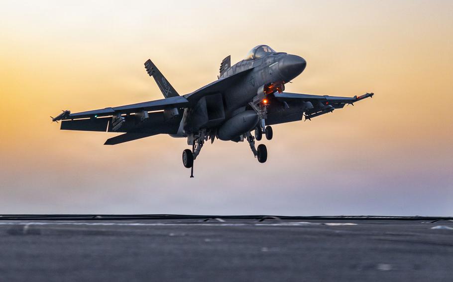 The fighter jet comes in for a landing with orange skies in the background.