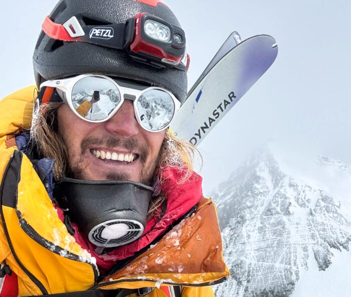 Close shot of Bartek Ziemski on the summit of Lhotse, Everest in background.