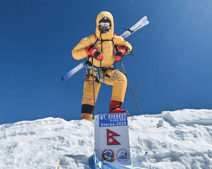 Bartek Ziemski stands on the sumit of everest with skis strapped to his bckpack and an air-trimming mask.