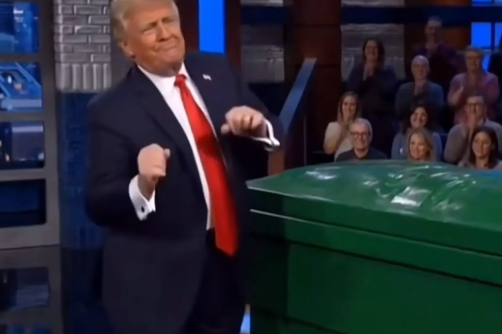 President Donald Trump dances to "YMCA" after throwing Steph Colbert into a green dumpster in an AI-generated clip posted to Truth Social on May 22, 2026