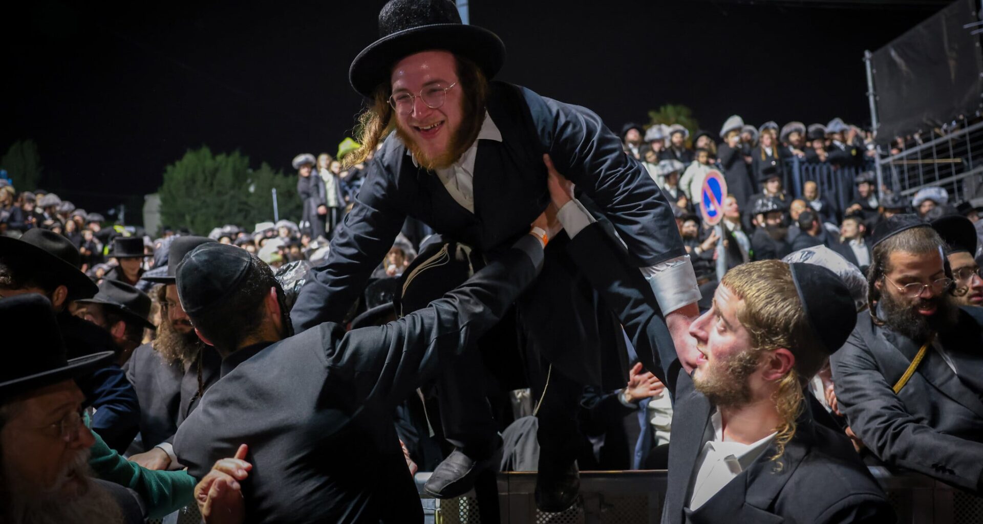 Ultra-Orthodox Jewish man hops a crowd control barrier at Mount Meron during Lag B'Omer celebrations on May 4, 2026. (David Cohen/Flash90)