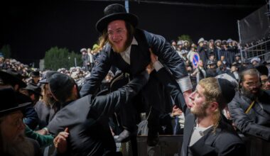 Ultra-Orthodox Jewish man hops a crowd control barrier at Mount Meron during Lag B'Omer celebrations on May 4, 2026. (David Cohen/Flash90)