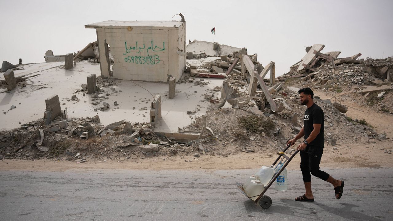 A Palestinian man carries water containers in Gaza City, Tuesday, May 12, 2026. (AP Photo/Abdel Kareem Hana)