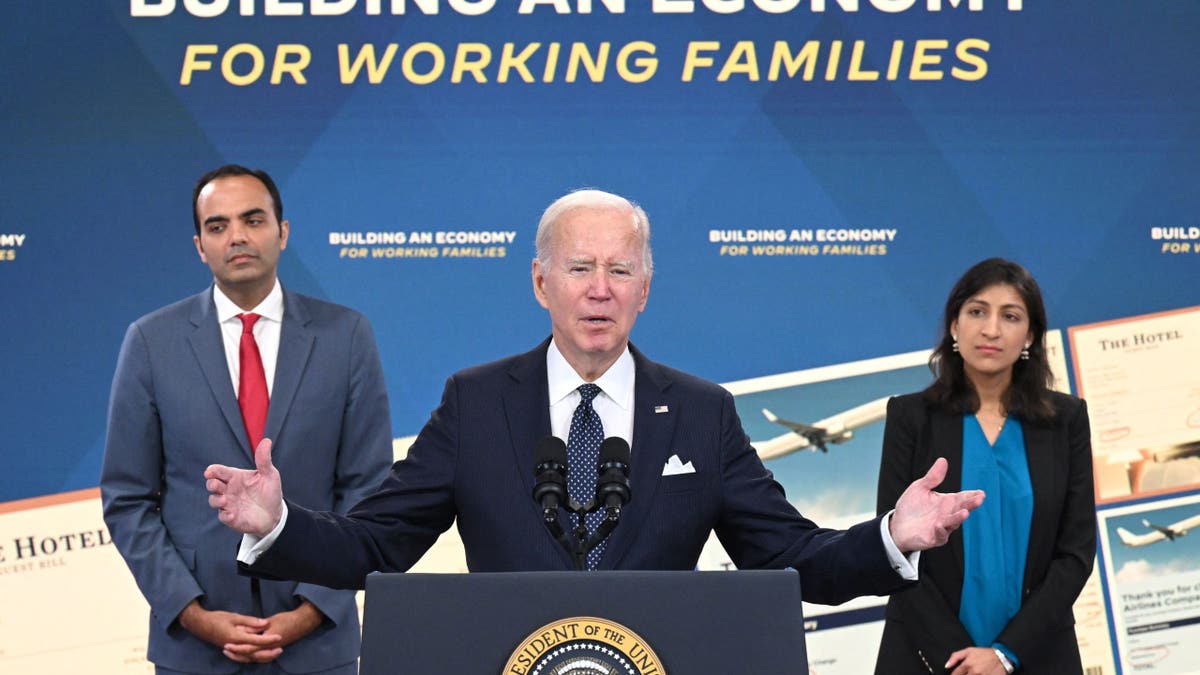 Consumer Financial Protection Bureau Director Rohit Chopra and Federal Trade Commission Chair Lina Khan listen as President Joe Biden speaks at the White House