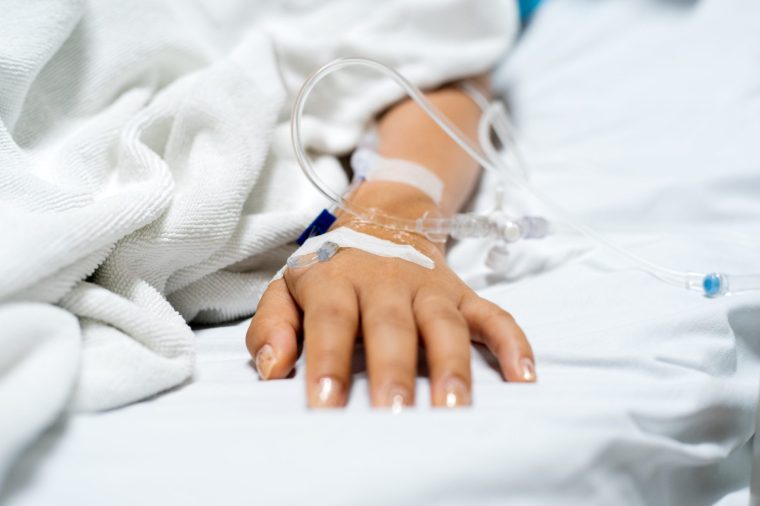 Young women patient's hand receiving IV drip medicine after surgery - stock photo