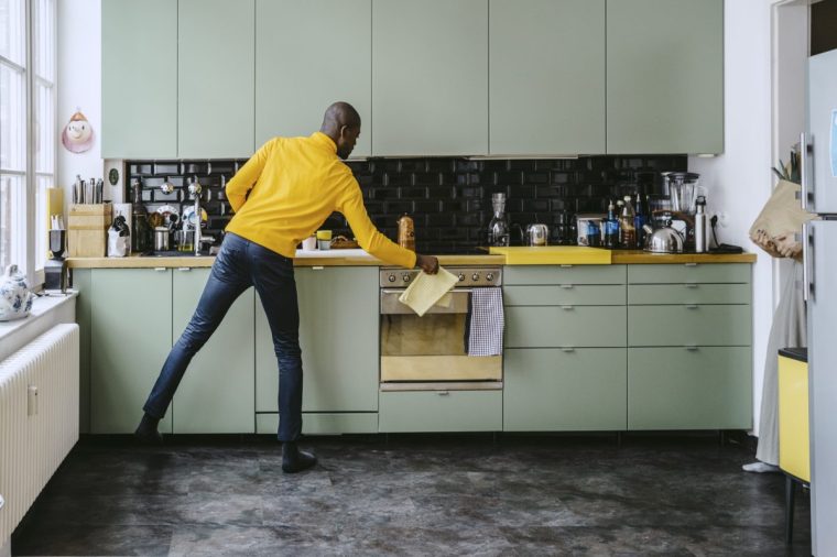Full length of mid adult man doing chores in kitchen at home - stock photo