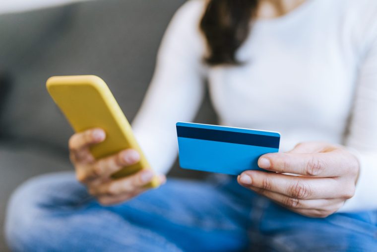 Close up of an unrecognizable woman shopping online with credit card via mobile phone - stock photo
