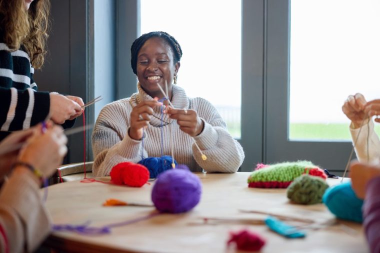 Woman learning to knit with friends in cafe - stock photo