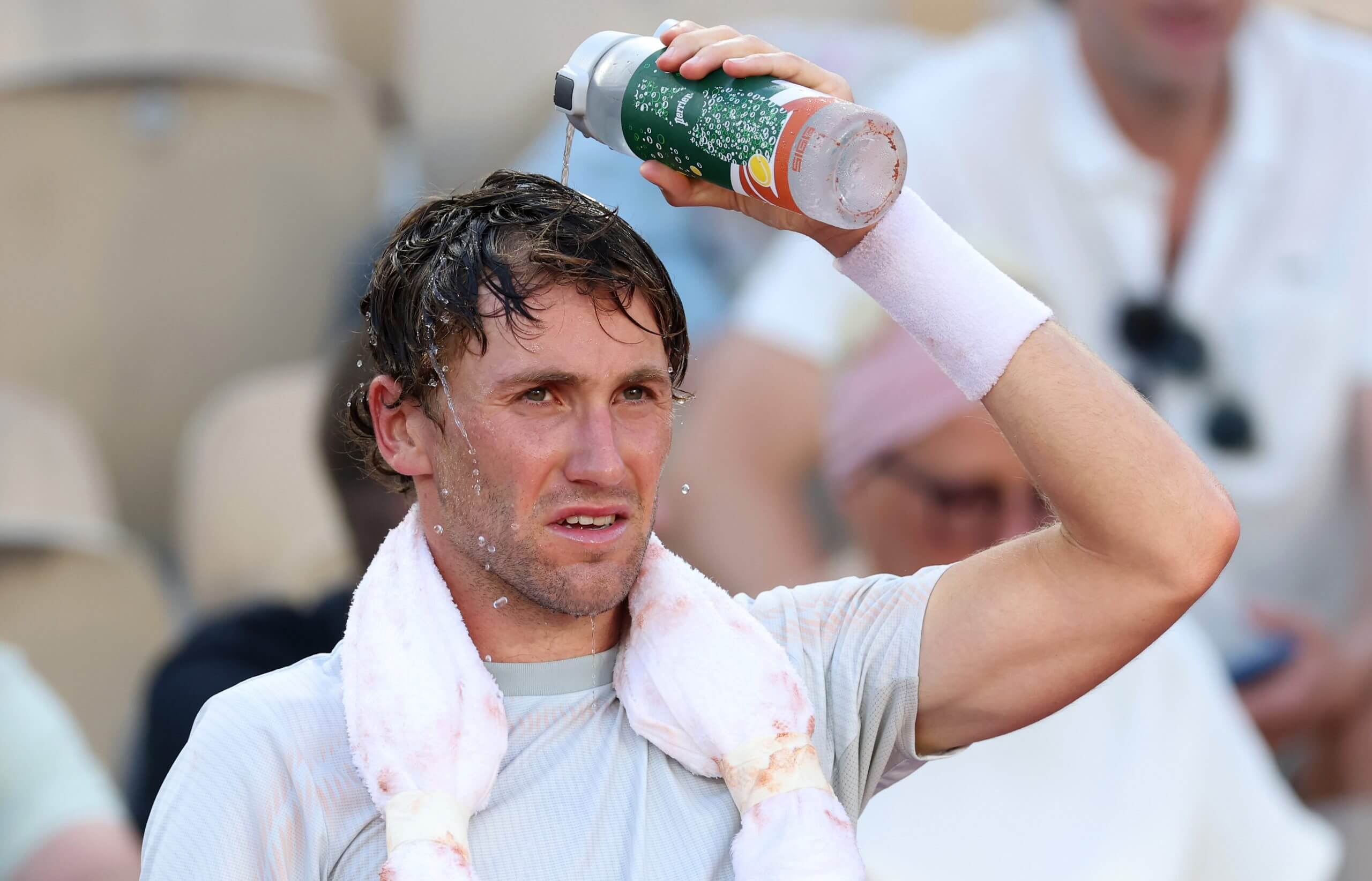 Casper Ruud pours water over his head with an ice towel around his neck.