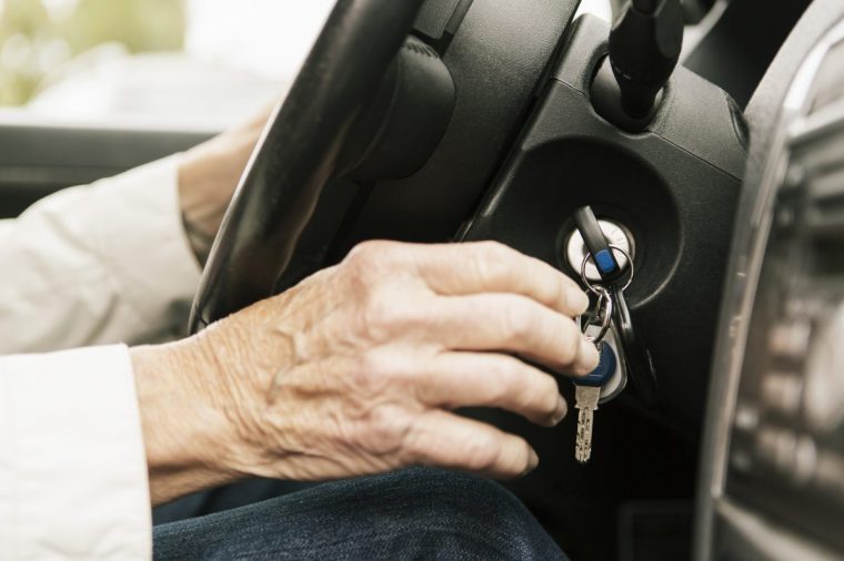 Cropped image of senior woman putting car key in ignition lock - stock photo
