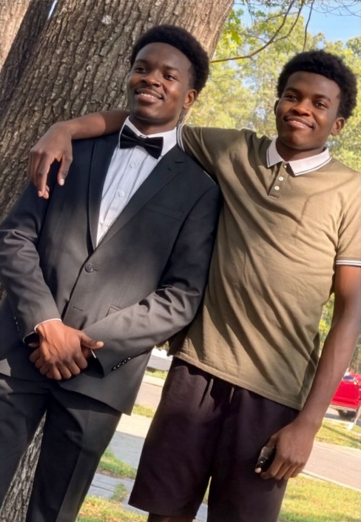 The Makoka brothers standing outside, the taller brother's arm over the shorter brother's shoulders