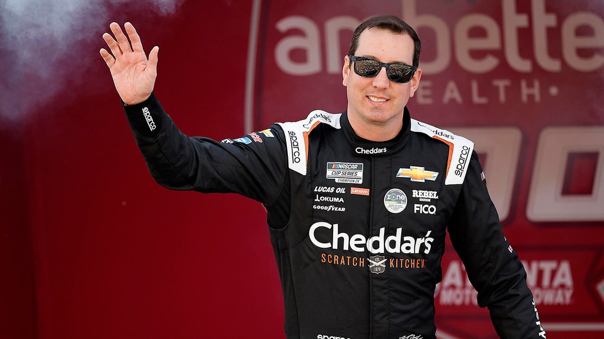 Kyle Busch waving to fans while walking onstage at Atlanta Motor Speedway