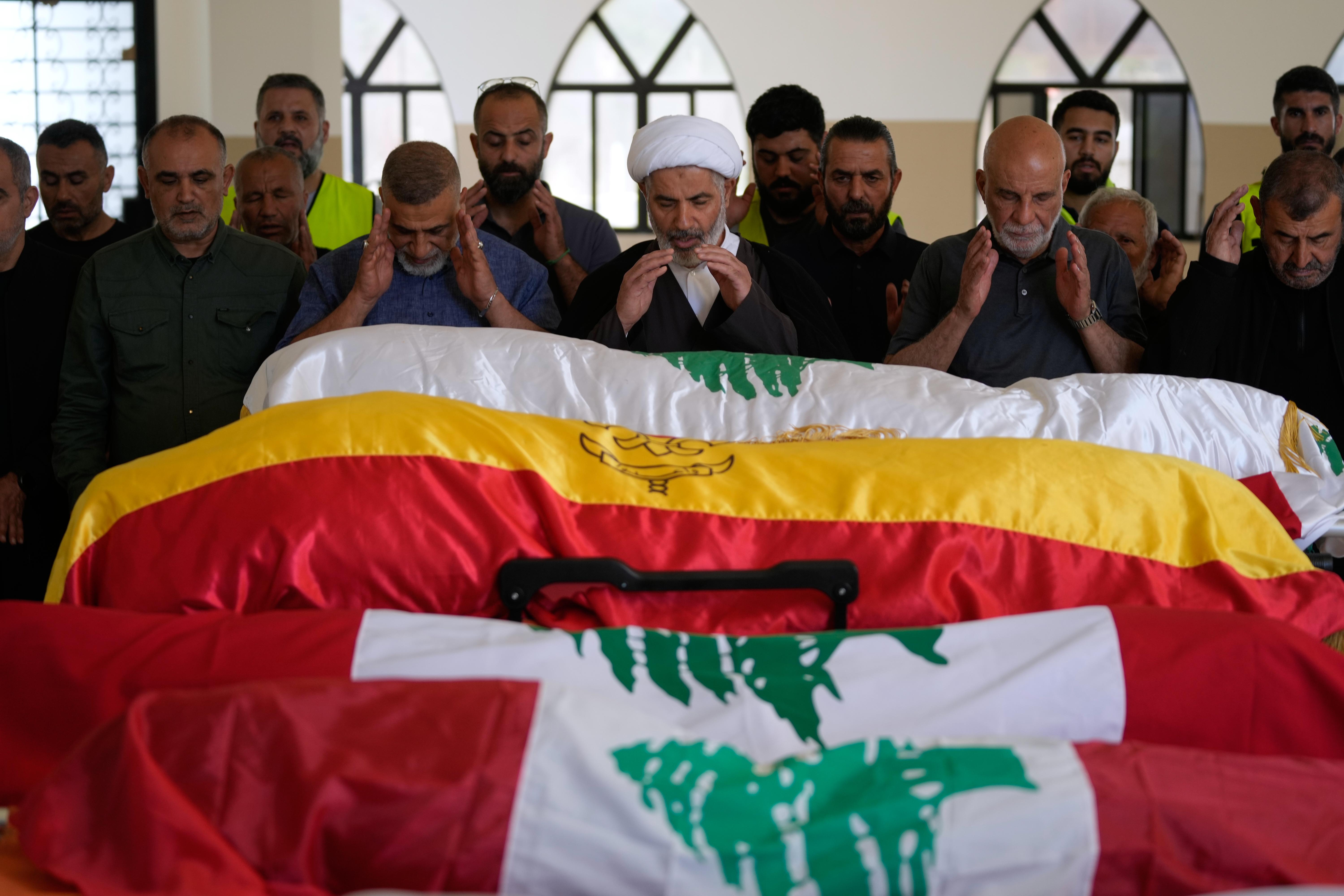 Mourners pray over the the bodies of family members killed by Israeli airstrike