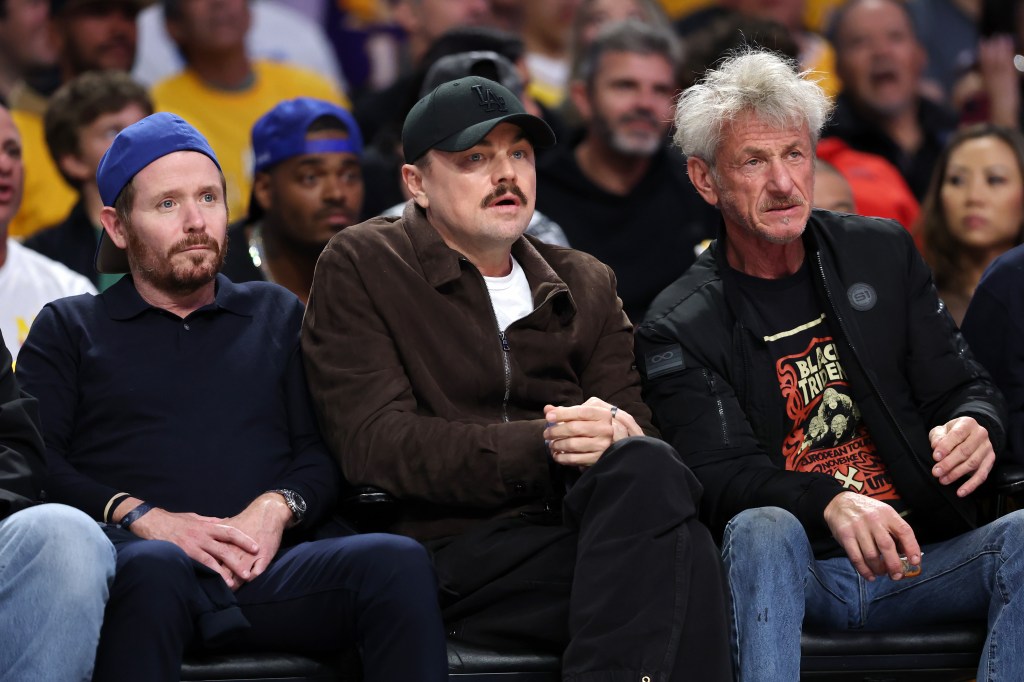 Actors Ethan Suplee, Leonardo DiCaprio, and Sean Penn sitting courtside at a basketball game.