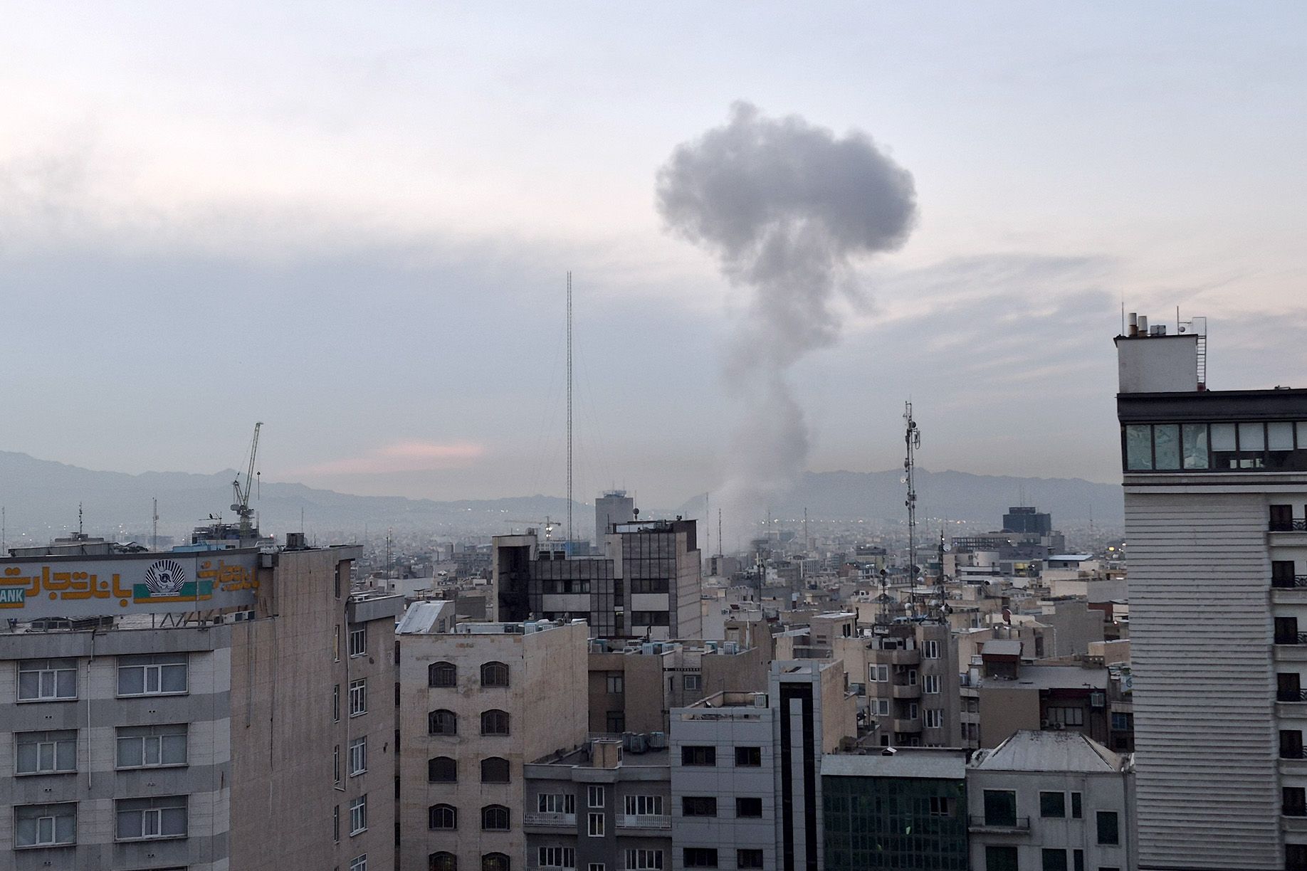 A photo shows smoke from an explosion rising in the middle of a cityscape. 