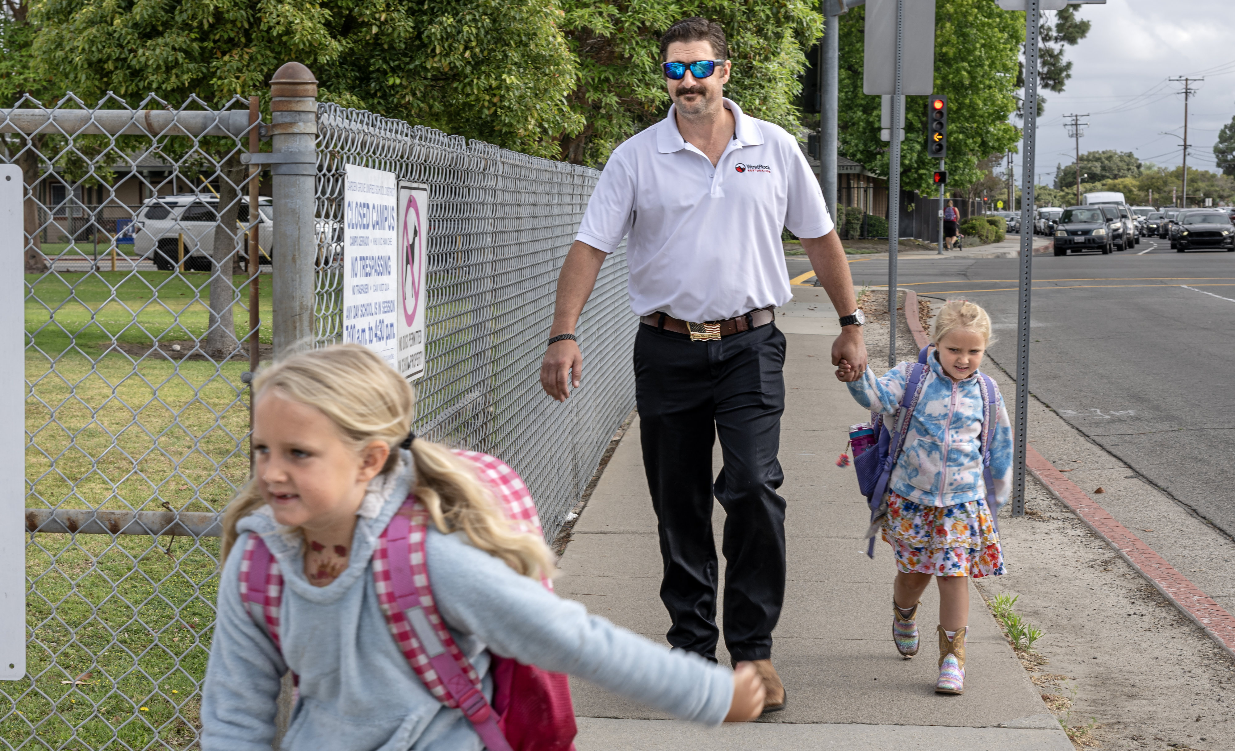 Jonathan Wighton walks his daughters, Alice, 7, left, and Kelly,...