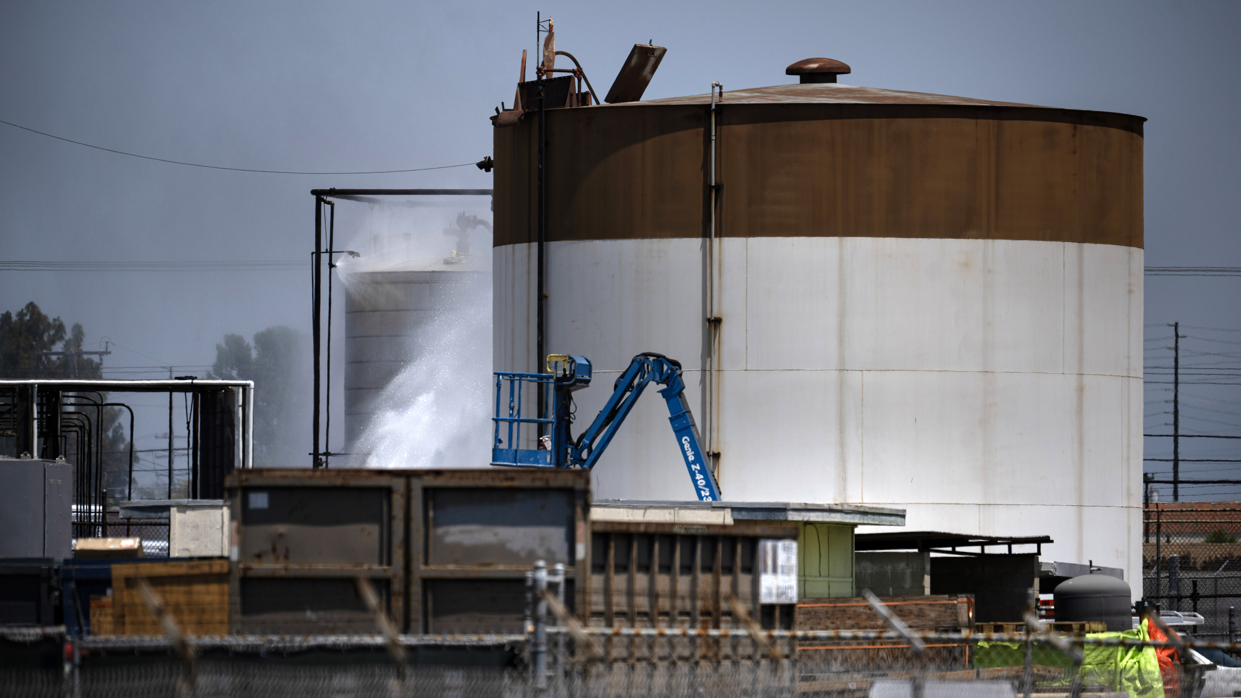 Water continues to spray on an overheated 34,000-gallon tank at...