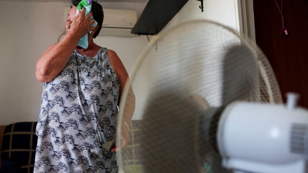 Monica Garcia, 65, wipes her sweat with a cloth while standing in front of a fan, as residents of Canada Real neighbourhood struggle with scorching temperatures amid first heatwave of the summer, in Madrid, Spain, June 26, 2023. The mother-of-three, who has lived at the shanty town for over 20 years, is waiting to be rehoused after a fire burnt her previous home. REUTERS/Isabel Infantes/