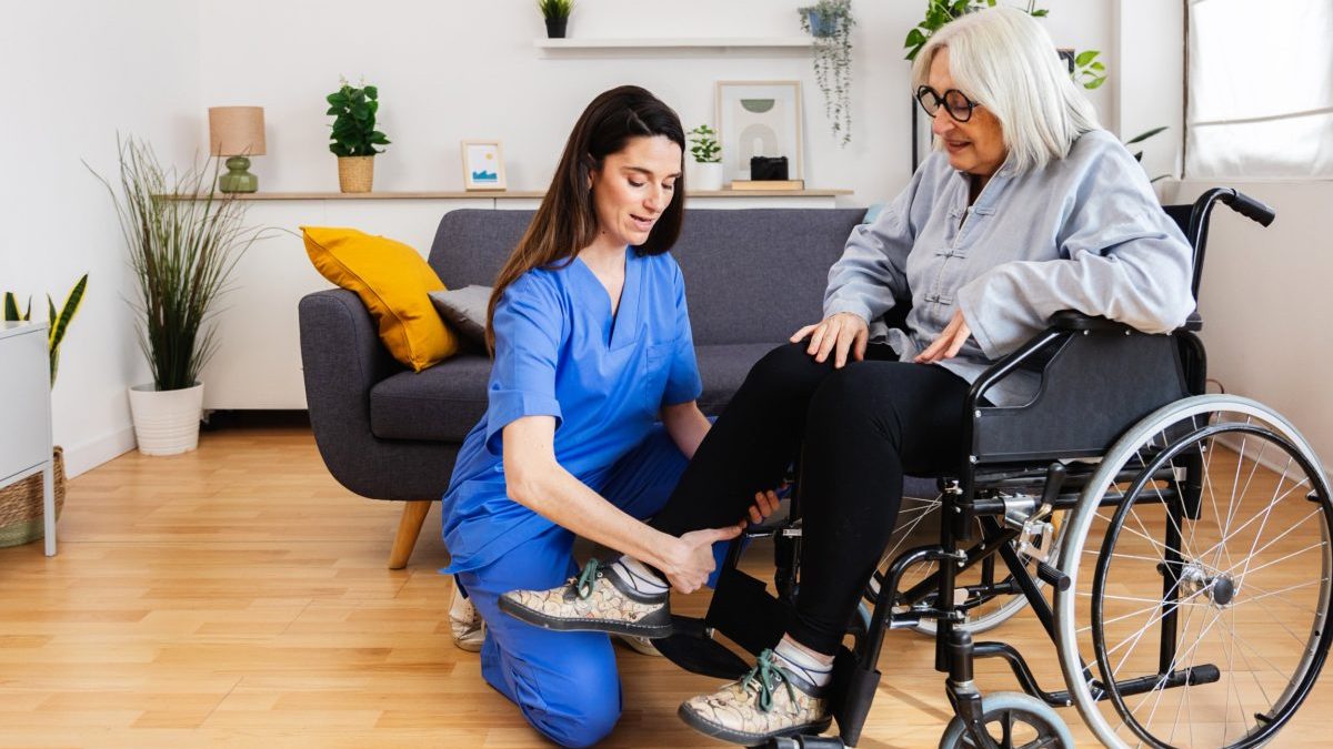 A woman in a wheelchair is helped by a caregiver