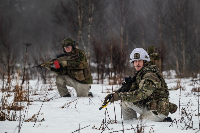Soldiers take up positions during an attack simulation involving the Norwegian 133 Air Wing Force Protection battalion and the British 51 Squadron RAF Regiment at Evenes Airbase, near Narvik on March 11, 2026, as NATO conducts its Cold Response military exercise. The Norwegian-led winter exercise involves 32.000 troops, 100 aircraft, and 30 warships from 14 nations taking part in high intensity, multi-domain operations in an arctic climate. (Photo by John MACDOUGALL / AFP via Getty Images)