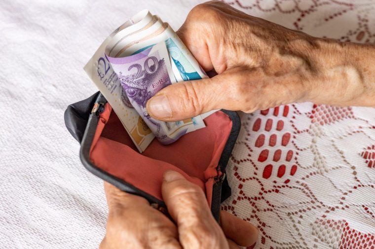 UK pound. A pensioner holds a wallet with money. Financial concept. Pensions in Britain