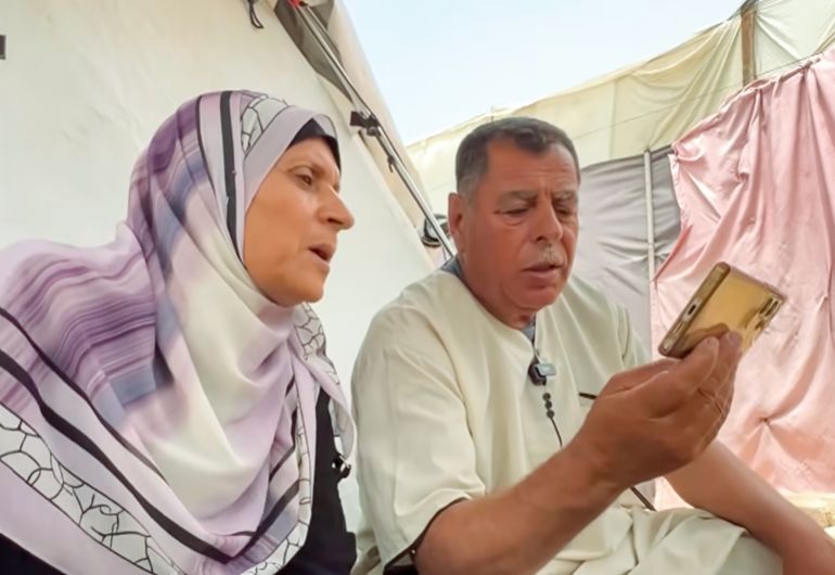 Adnan Abu Foul and his wife, Um Ibrahim, watch Hajj rituals on a mobile phone from their tent in Gaza. They have been barred from traveling to the pilgrimage for three consecutive years [Screengrab/Al Jazeera]