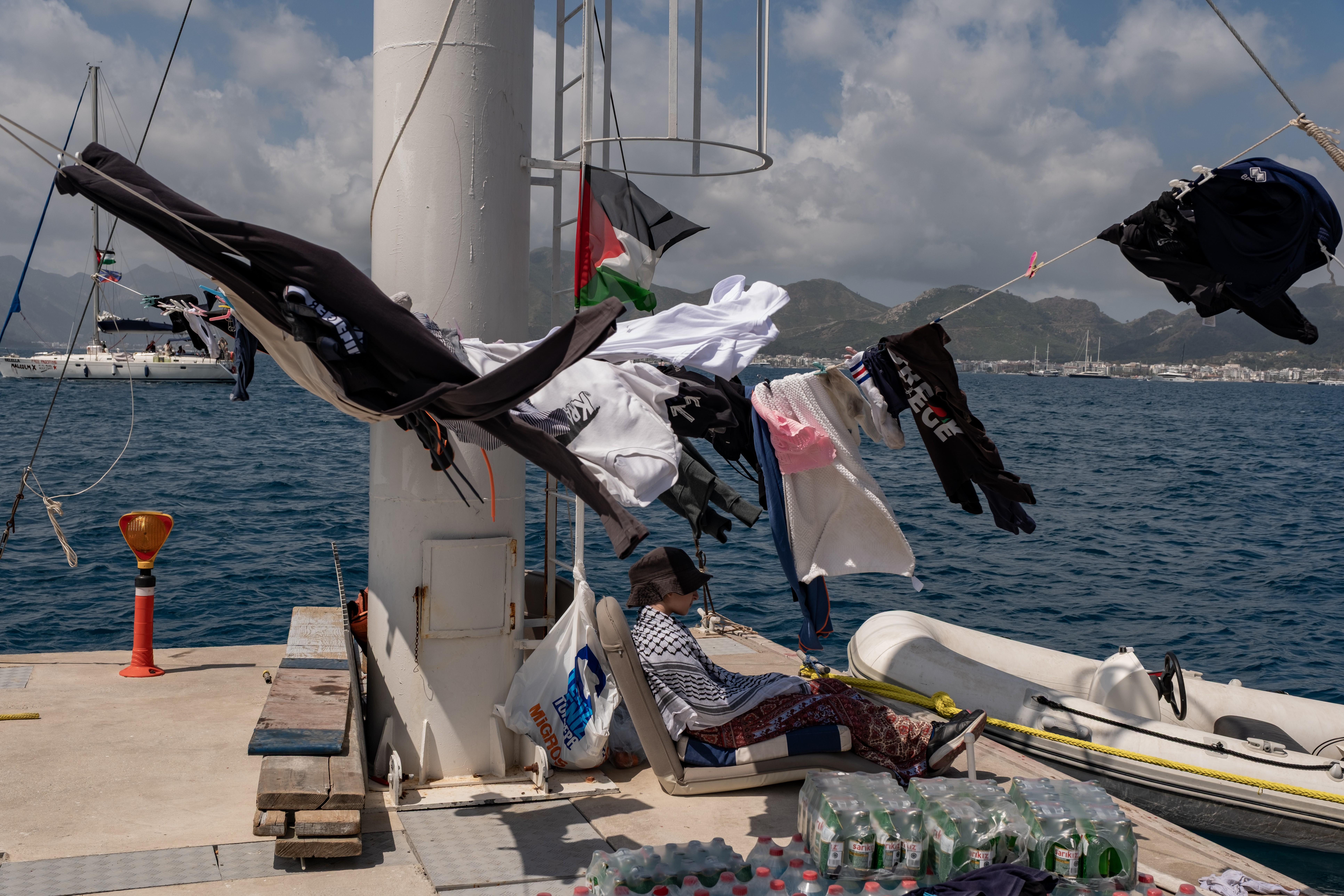 An activist chants while hanging Palestinian flags on a boat belonging to the Global Sumud Flotilla.