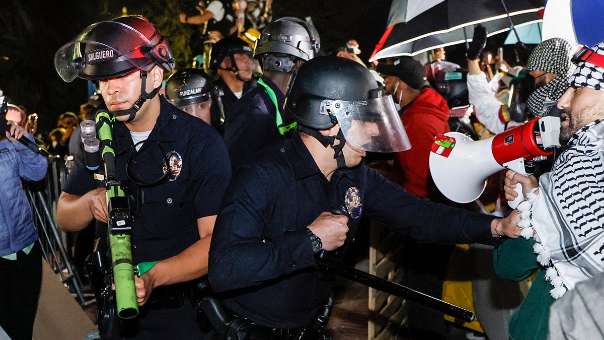 Police officers reacting while anti-Israel students stand their ground at UCLA campus