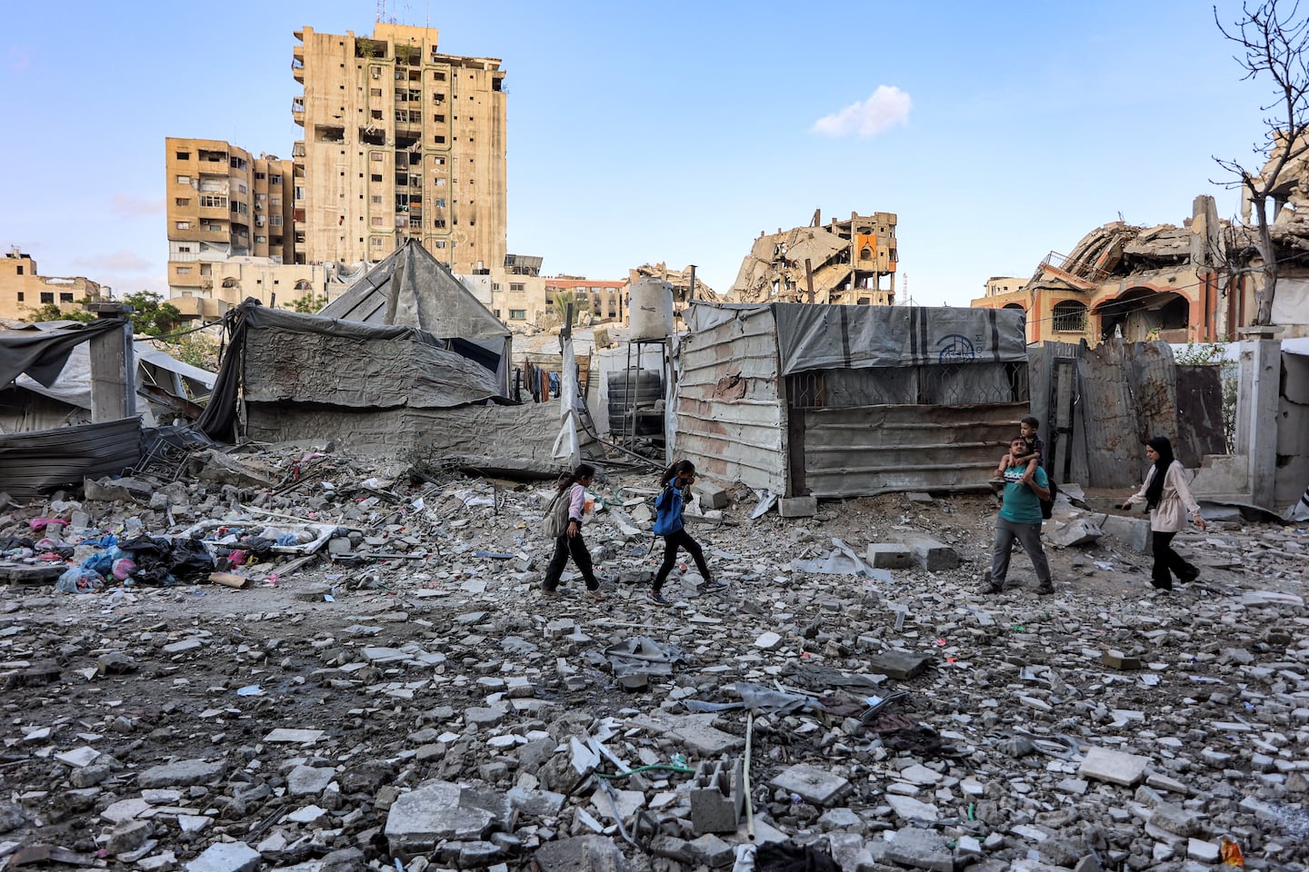 People walk outside a residential building that was hit by an Israeli strike the previous day in the Rimal neighbourhood of Gaza City on May 16, 2026. Israel said on May 15 that it carried out a strike in Gaza targeting Ezzedine Al-Haddad, who described it as chief of the armed wing of Palestinian movement Hamas. Since Hamas's Oct. 7, 2023 attack on Israel, the Israeli military and intelligence services have waged an extensive campaign targeting the group's senior political leaders and militant commanders in Gaza and across the region.