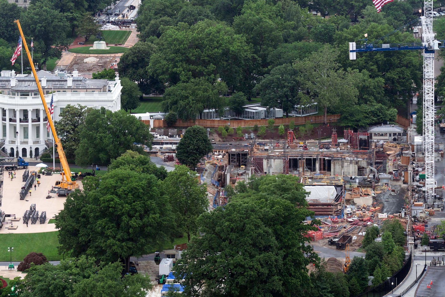 Work continued on the construction of the ballroom at the White House (right) while a UFC cage was being built on the South Lawn, on Saturday.  