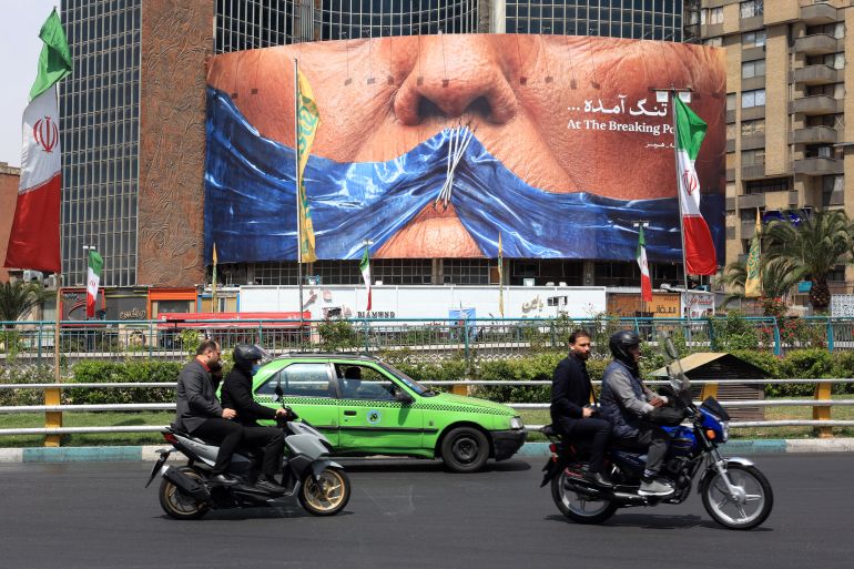 Motorists make their way past an anti-US billboard referring to President Donald Trump and the Strait of Hormuz, installed on a building at the Valiasr Square in Tehran on May 2, 2026.