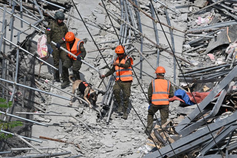 Military personnel with a working dog conduct search and rescue operations at a collapsed building in Angeles City, Pampanga province, north of Manila on May 25, 2026.