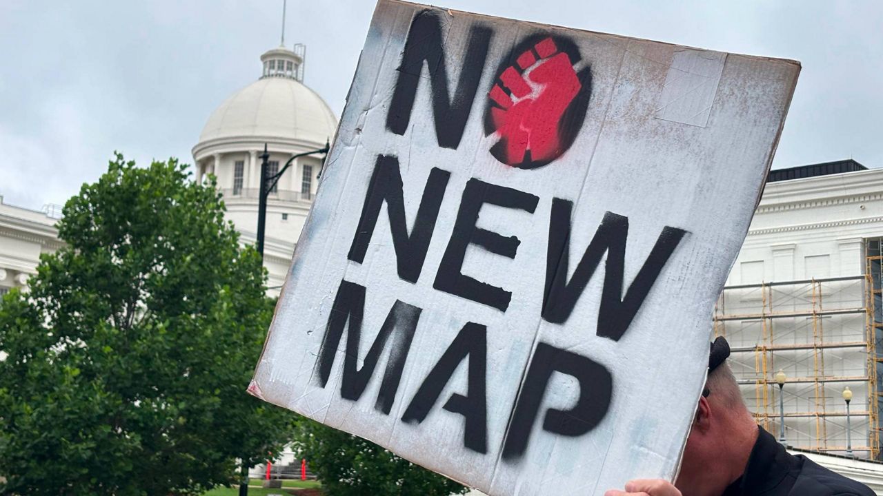 A demonstrator holds up a sign outside the Alabama Statehouse in Montgomery, Ala., on Thursday, May, 7 2026. (AP Photo/Kim Chandler)