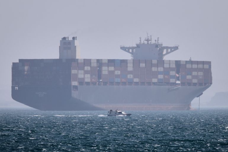 A container ship sits at anchor as a small motorboat passes in the foreground in the Strait of Hormuz off Bandar Abbas, Iran, Saturday, May 2, 2026. (Amirhosein Khorgooi/ISNA via AP)