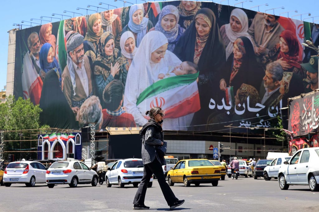 A woman crosses a street near a large political billboard in central Tehran on Tuesday. Photo: AFP