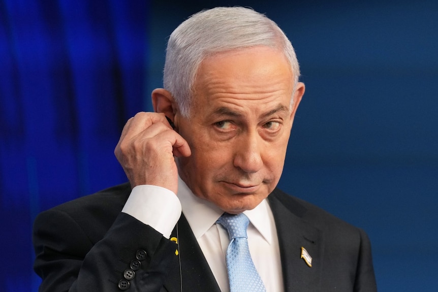 A man in a suit looks on.