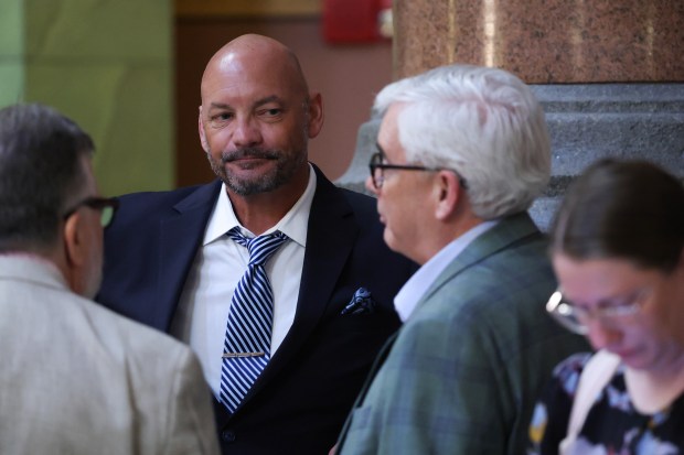 Marc Poulos, center left, talks with colleagues outside the House chamber during the spring legislative session at the State Capitol, May 30, 2026, in Springfield. (John J. Kim/Chicago Tribune)