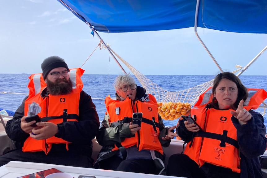 three people in life jackets on a boat