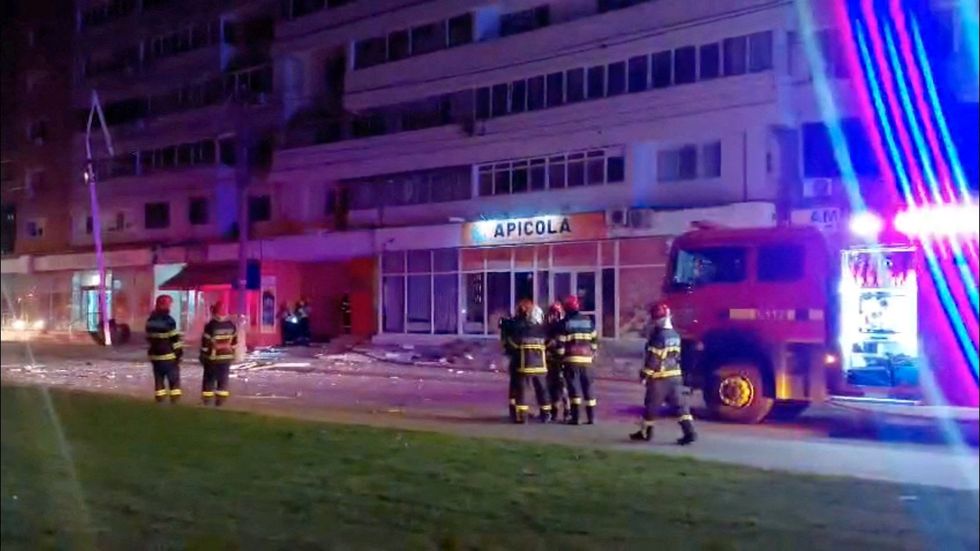 Firefighters work near the apartment block which was hit by a Russian drone