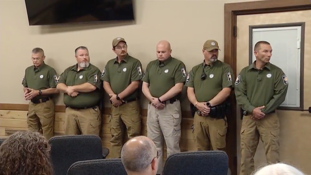Six Cohutta police officers in olive shirts and khaki pants standing in a room.