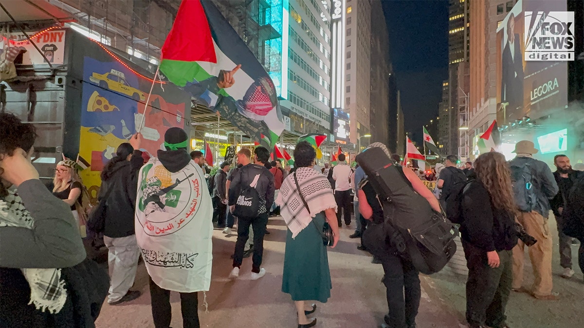 Demonstrators carrying imagery of Abu Obaida and Palestinian flags in Times Square New York City