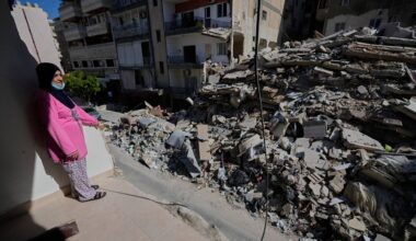 Em Ali Khodor, 75, looks through her damaged apartment into a destroyed building that was hit few weeks ago by an Israeli airstrikeafter she returns to the house, in the southern port city of Tyre, Lebanon, Thursday, April 30, 2026. (AP Photo/Hussein Malla)