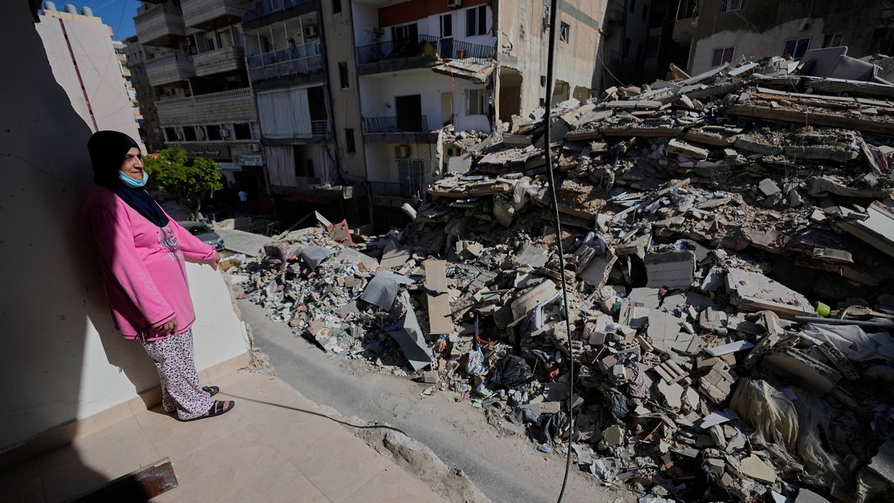Em Ali Khodor, 75, looks through her damaged apartment into a destroyed building that was hit few weeks ago by an Israeli airstrikeafter she returns to the house, in the southern port city of Tyre, Lebanon, Thursday, April 30, 2026. (AP Photo/Hussein Malla)