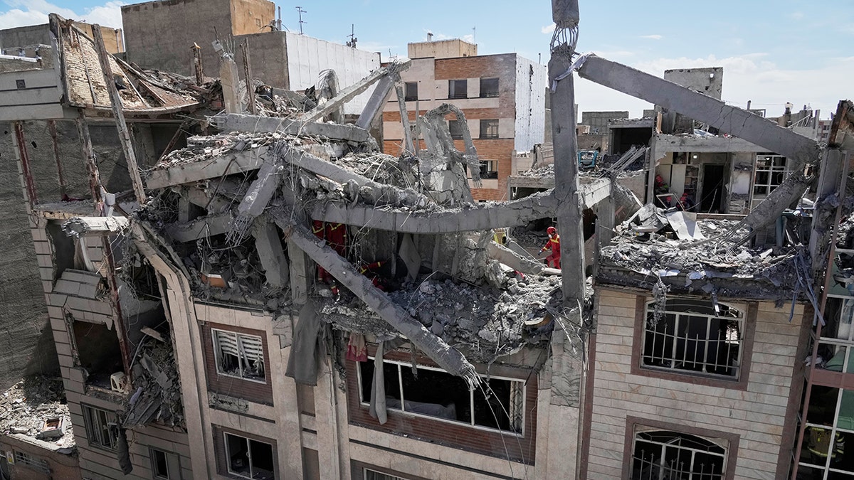 First responders inspecting a damaged residential building in Tehran.
